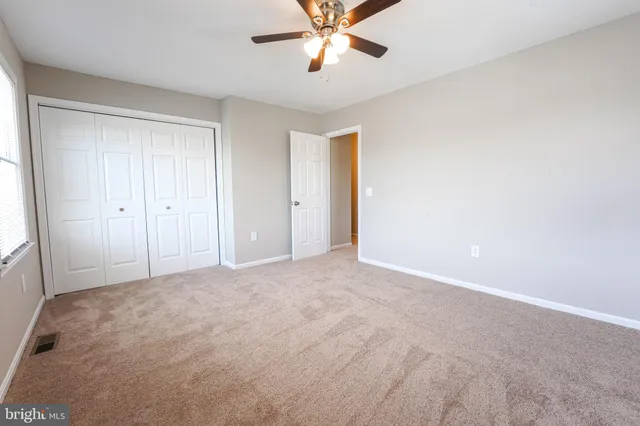 a view of an empty room and chandelier fan