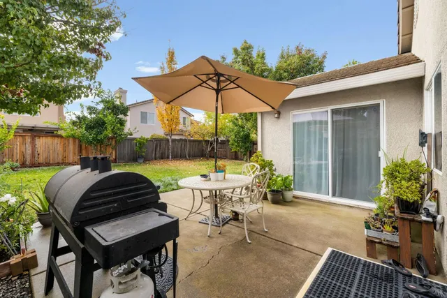 a view of a patio with table and chairs under an umbrella with potted plants