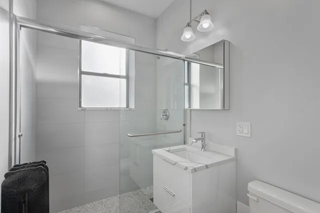 a bathroom with a granite countertop sink toilet and mirror