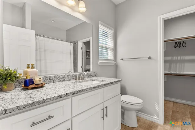 a bathroom with a granite countertop sink a toilet and a mirror