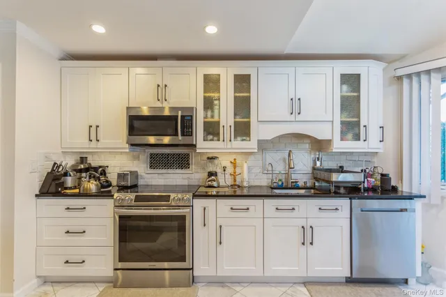 a kitchen with stainless steel appliances granite countertop a stove a sink and a microwave