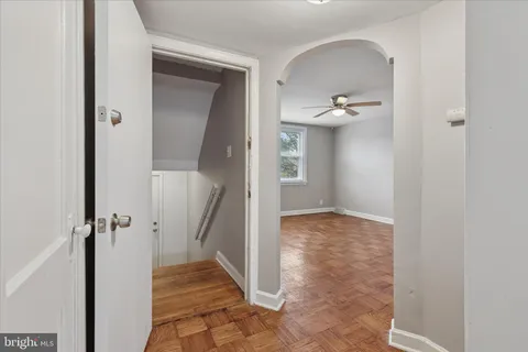 a view of a hallway with wooden floor and a bathroom