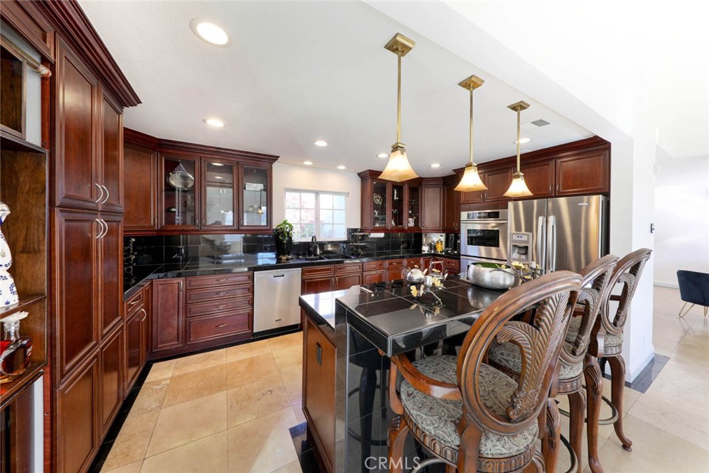 20975 Sequoia Lane Mission Viejo, CA 92691 - Photo 14 of 47 a kitchen with stainless steel appliances kitchen island granite countertop a refrigerator a sink a stove and chairs with wooden floor
