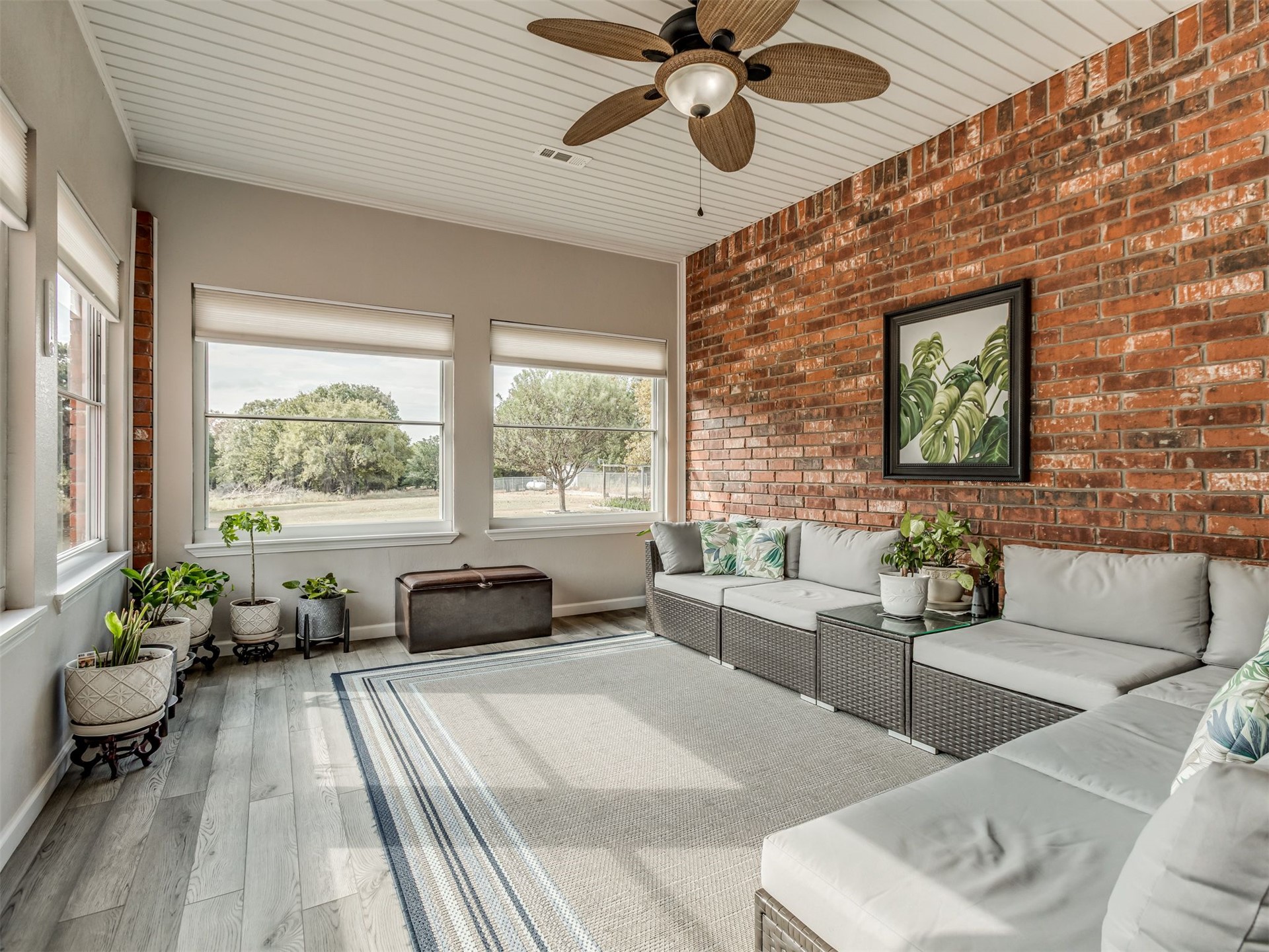 119 Mainsail Road Stigler, OK 74462 - Photo 35 of 52 Exposed brick accent wall, wood-finish flooring, multiple windows with roller shades, white paneled ceiling, and a ceiling fan with integrated lighting