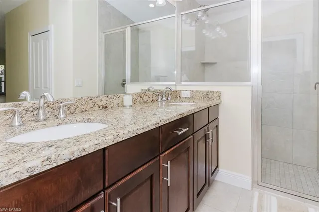 a bathroom with a granite countertop sink a mirror and a shower