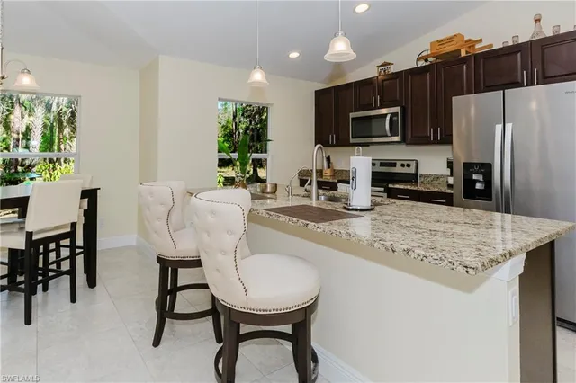 a kitchen with stainless steel appliances granite countertop a table chairs microwave and refrigerator