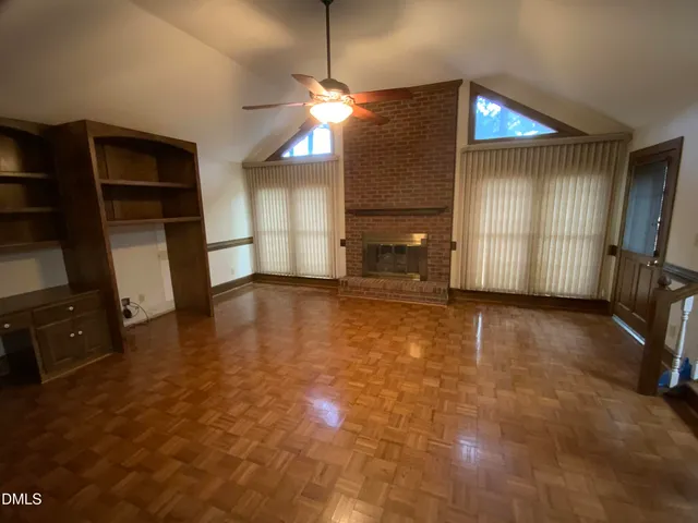 an empty room with a chandelier fan and windows