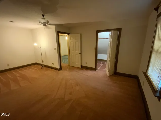a view of an empty room and window and chandelier fan
