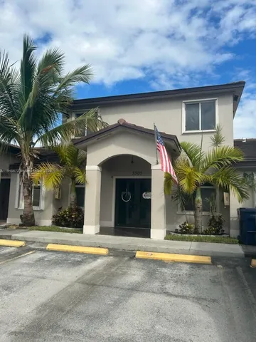 a view of a house with a swimming pool and a lawn chairs under an umbrella