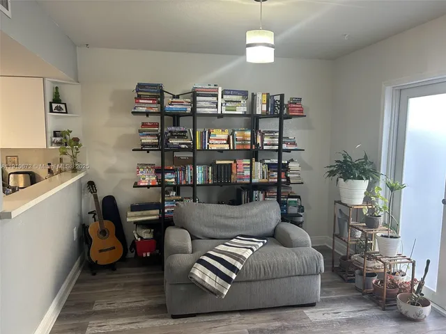 a living room with furniture with kitchen view and a potted plant