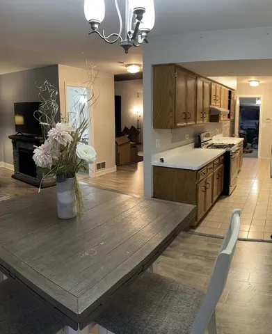 a large kitchen with kitchen island a stove a sink dishwasher and a fireplace with wooden floor