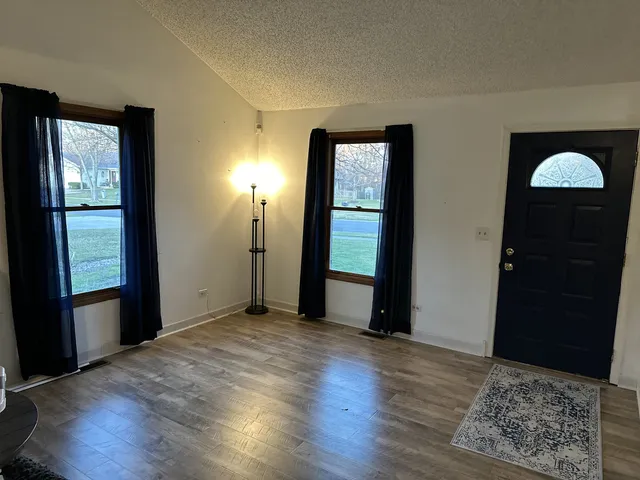 an empty room with wooden floor cabinet and windows