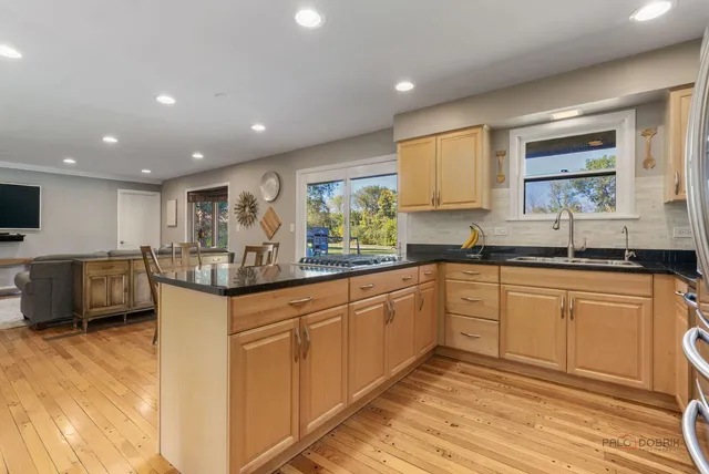 a kitchen with stainless steel appliances granite countertop a refrigerator a sink and a stove with wooden floor