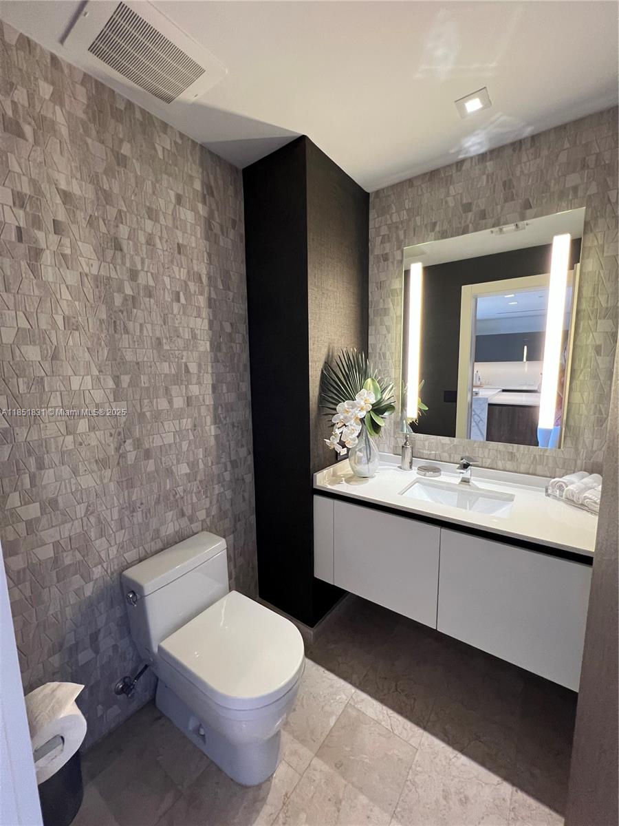 88 Southwest 7th Street, Unit 3007 Miami, FL 33130 - Photo 15 of 36 a bathroom with a granite countertop toilet sink and mirror