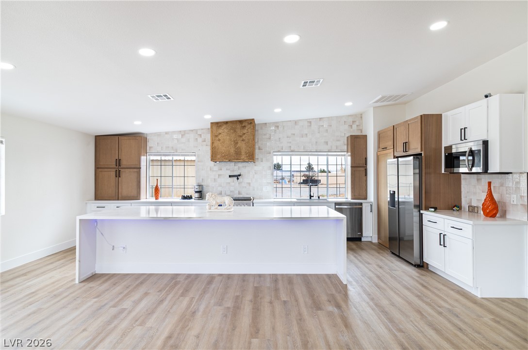 1891 Brian Road Pahrump, NV 89048 - Photo 5 of 50 Kitchen with visible vents, light wood-style flooring, backsplash, appliances with stainless steel finishes, and light countertops