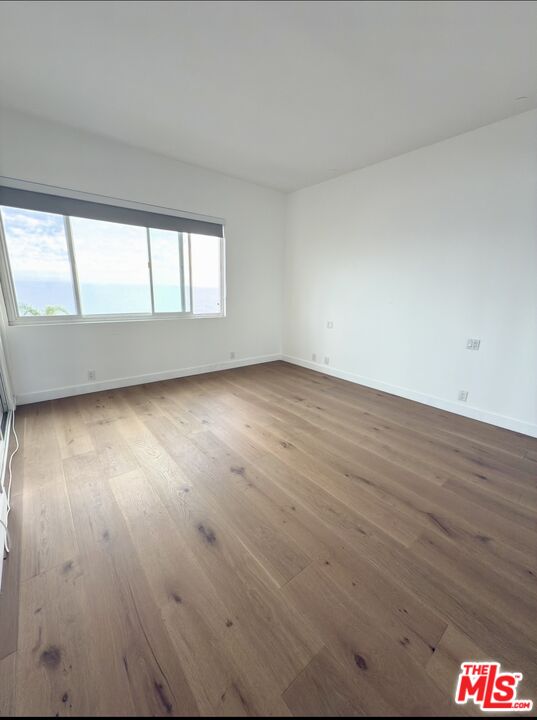 18069 Coastline Drive, Unit 9 Malibu, CA 90265 - Photo 14 of 22 an empty room with wooden floor and windows