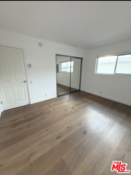 18069 Coastline Drive, Unit 9 Malibu, CA 90265 - Photo 19 of 22 an empty room with wooden floor and windows