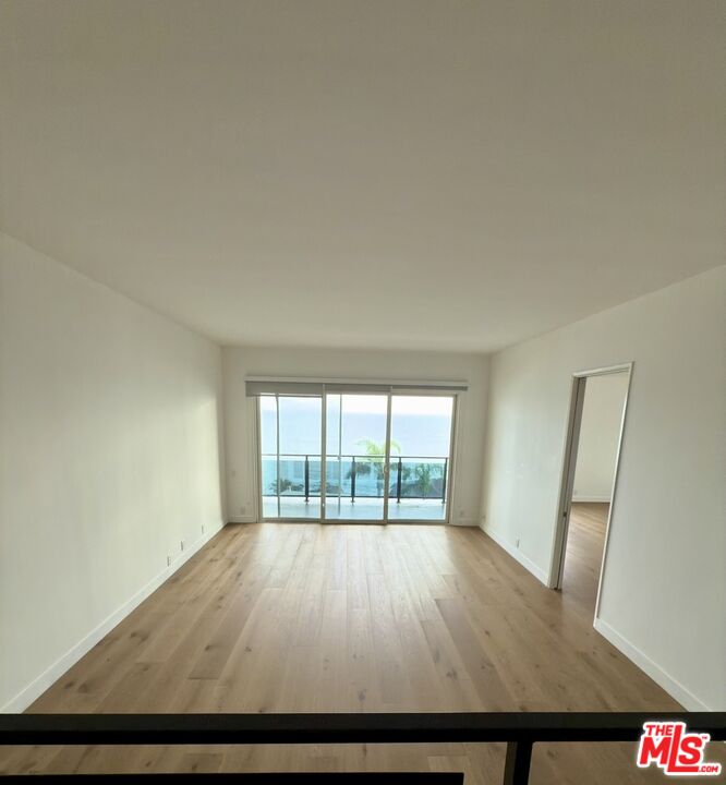 18069 Coastline Drive, Unit 9 Malibu, CA 90265 - Photo 10 of 22 an empty room with wooden floor and windows