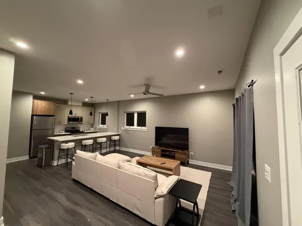 a living room with stainless steel appliances furniture and a flat screen tv