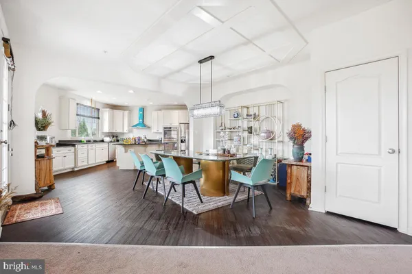 a living room with stainless steel appliances kitchen island granite countertop furniture and a wooden floor