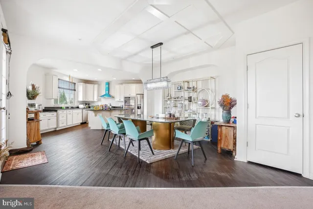 a living room with stainless steel appliances kitchen island granite countertop furniture and a wooden floor