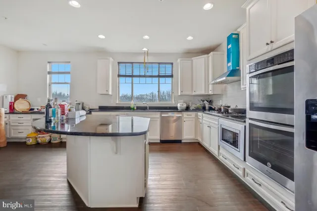 a kitchen with kitchen island granite countertop a sink cabinets and stainless steel appliances