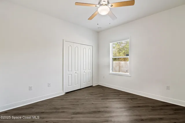 an empty room with wooden floor fan and windows