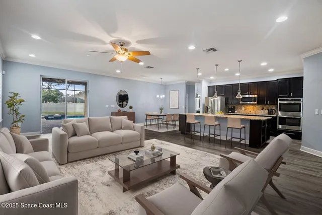 a living room with furniture kitchen view and a chandelier