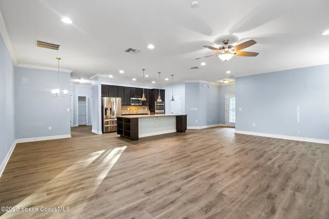 a view of an empty room with kitchen and a window