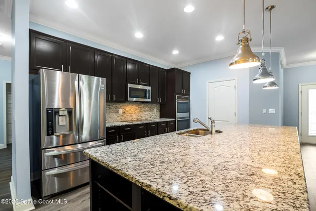 a kitchen with stainless steel appliances granite countertop a sink a stove and refrigerator