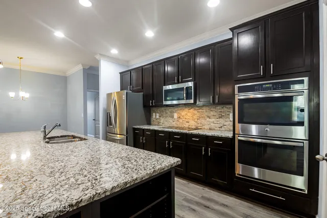 a kitchen with kitchen island granite countertop stainless steel appliances and sink