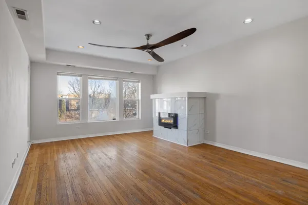 a view of empty room with wooden floor and fan