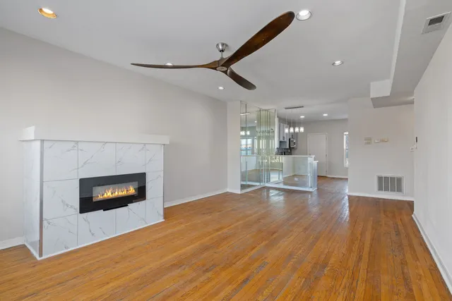 a living room with stainless steel appliances wooden floor and a fireplace