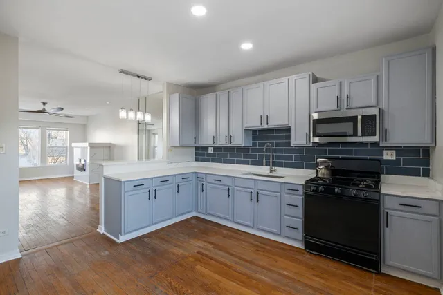 a large kitchen with cabinets wooden floor and stainless steel appliances