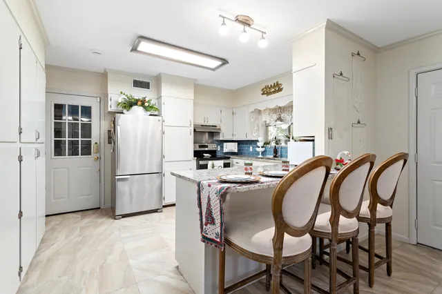 a kitchen with refrigerator a stove a dining table and chairs