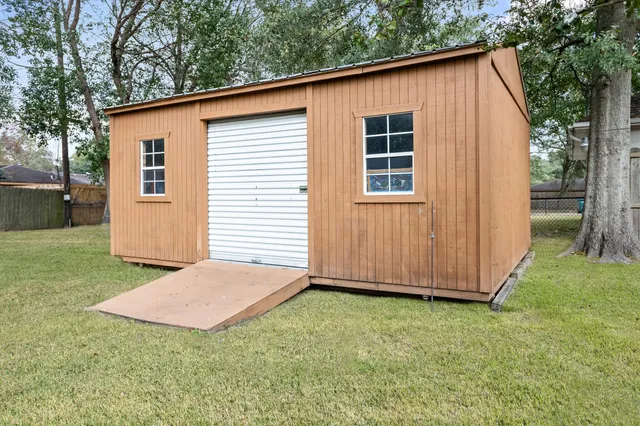 a view of backyard with small cabin and wooden fence