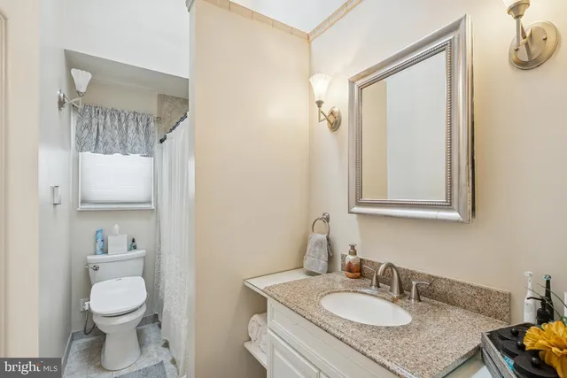 a bathroom with a granite countertop sink toilet and mirror