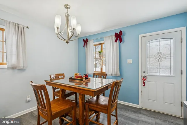 a dining room with wooden floor a chandelier a wooden table and chairs