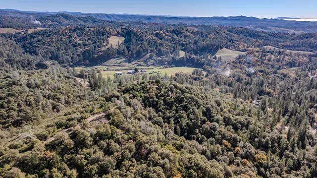 an aerial view of a houses with a yard and mountain
