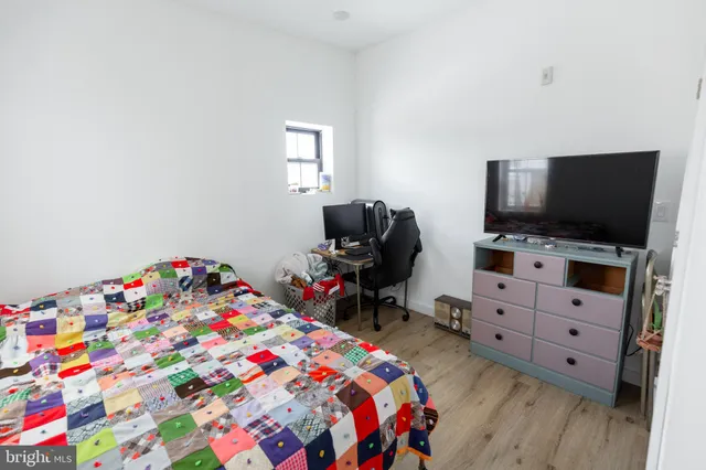 a bedroom with a bed and flat tv screen on the dresser