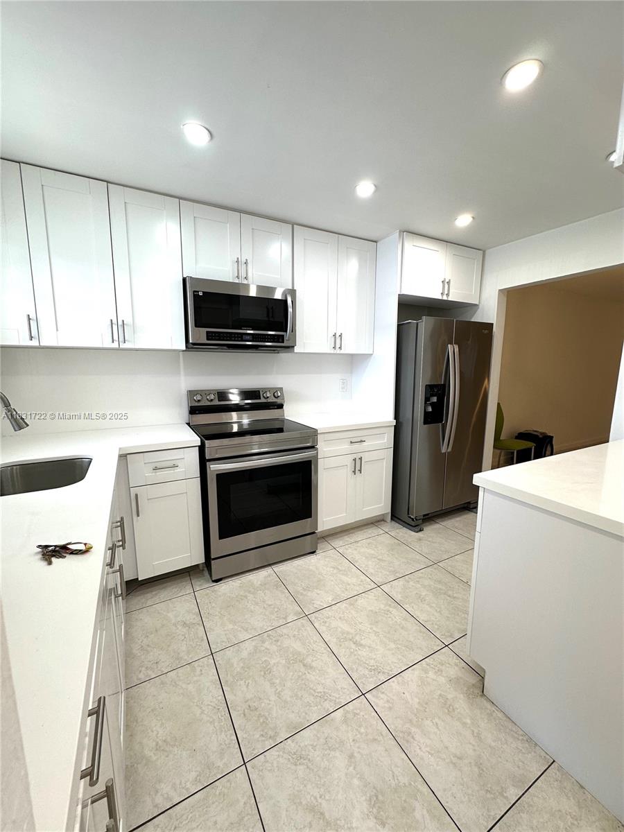a kitchen with a refrigerator a stove top oven and a sink with wooden floor