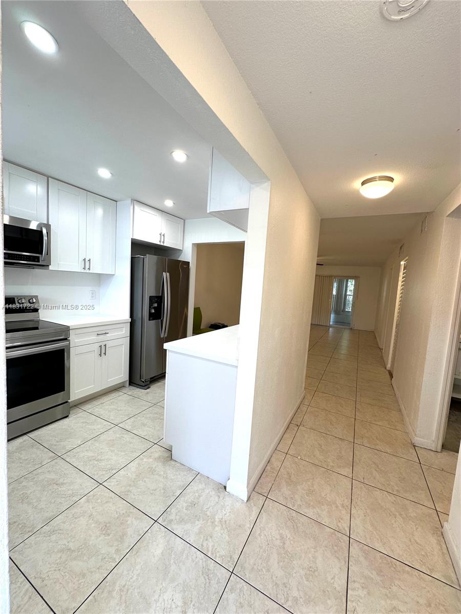 603 South State Road 7, Unit 1D Margate, FL 33068 - Photo 3 of 12 a view of a kitchen with refrigerator and white cabinets