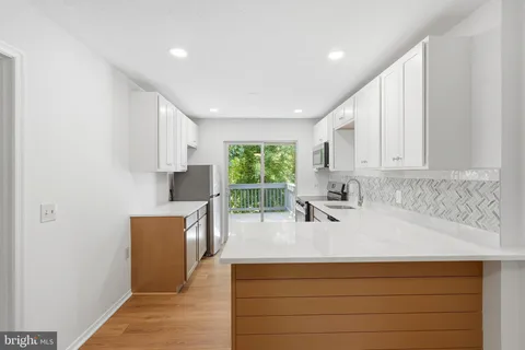 a kitchen with a sink a stove a refrigerator cabinets and a window