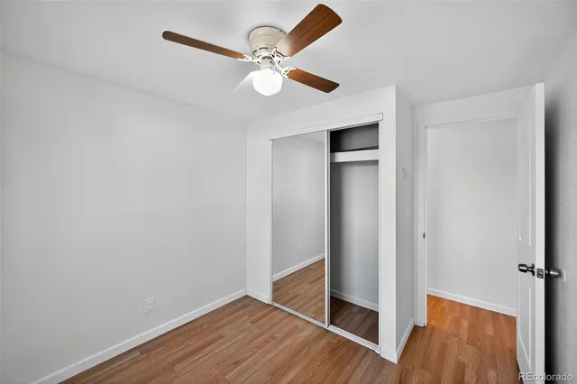 a view of empty room with wooden floor and fan