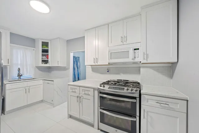 a kitchen with white cabinets and appliances