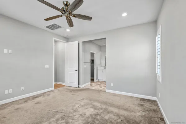 an empty room with closet and a chandelier fan