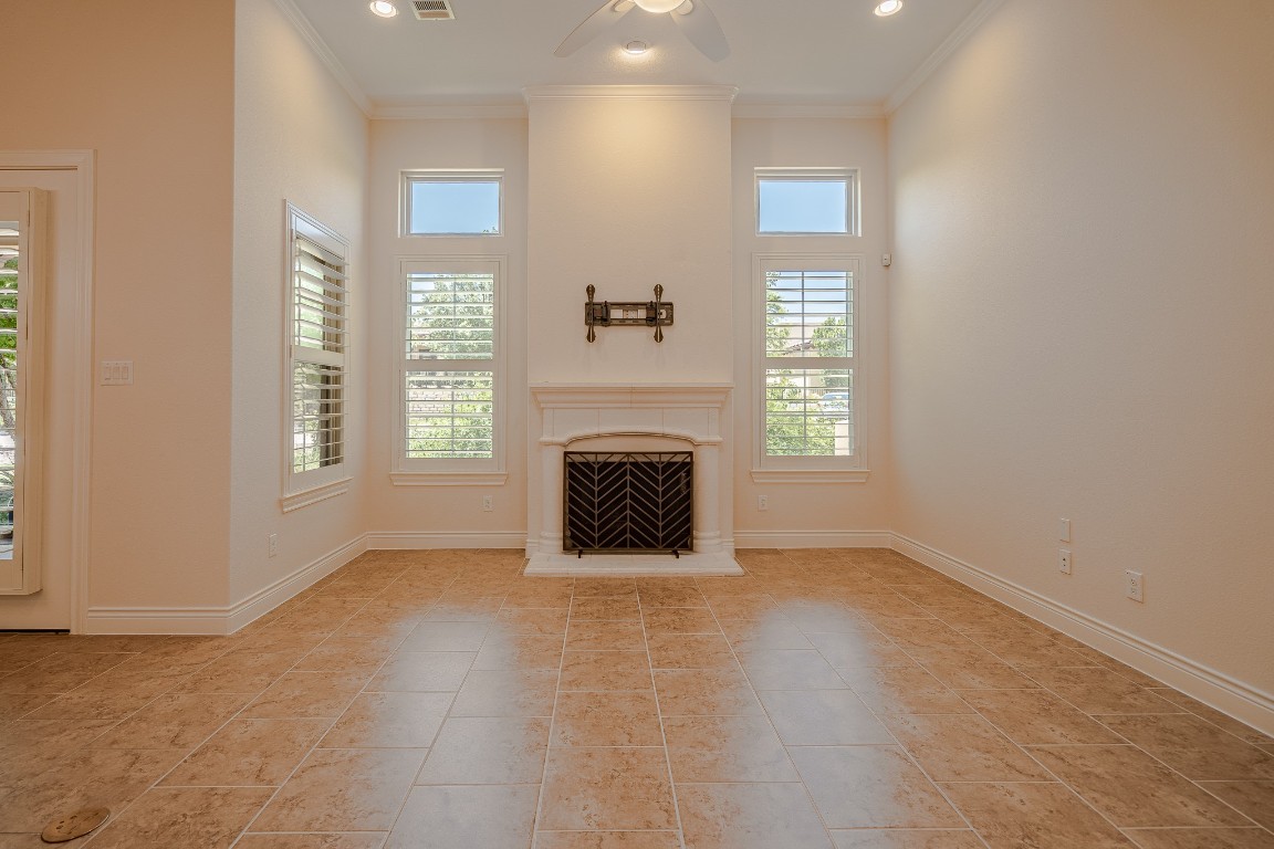 108-2 Rivalto Circle, Unit 5 Lakeway, TX 78734 - Photo 7 of 35 Unfurnished living room with ornamental molding, light tile patterned flooring, a fireplace with raised hearth, ceiling fan, and recessed lighting