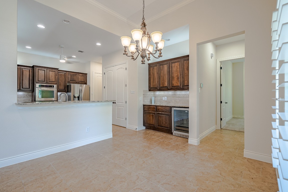 108-2 Rivalto Circle, Unit 5 Lakeway, TX 78734 - Photo 9 of 35 Kitchen with tasteful backsplash, dark brown cabinetry, wine cooler, appliances with stainless steel finishes, and a chandelier