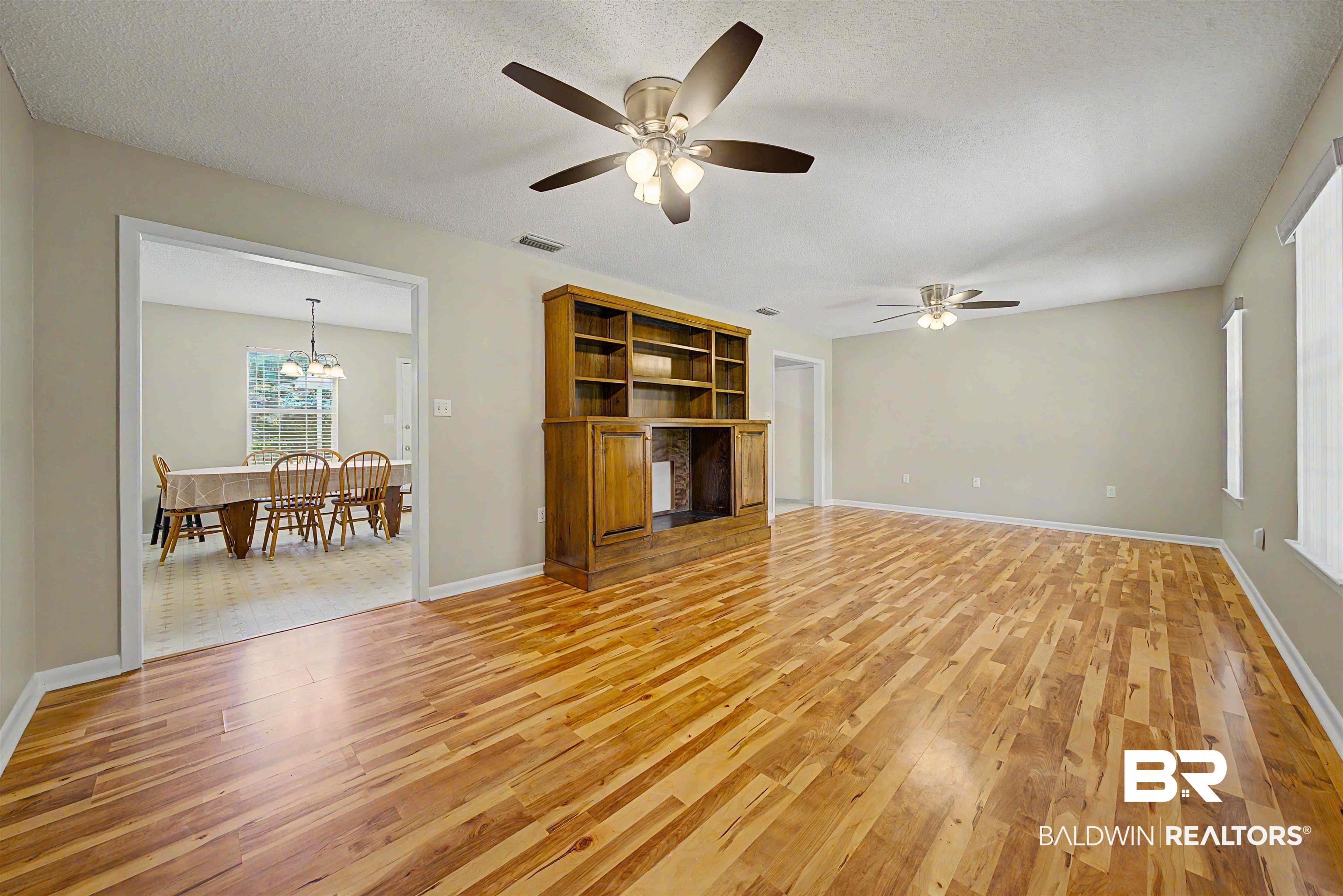 22963 Highway 98 Foley, AL 36535 - Photo 7 of 52 Spacious interior featuring wood-finish flooring, a built-in wood entertainment center with shelving, and multiple ceiling fans