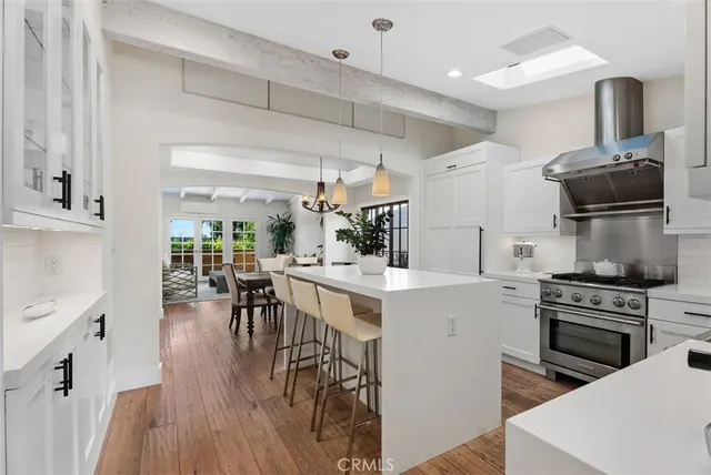 a kitchen with stainless steel appliances a stove a sink dishwasher and a dining table with wooden floor